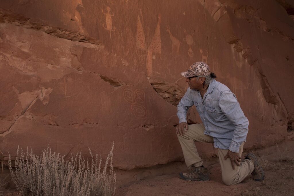 Jim Enote studies petroglyphs on a sandstone cliff in northwest New Mexico produced by a culture that vanished after a likely half-century drought.