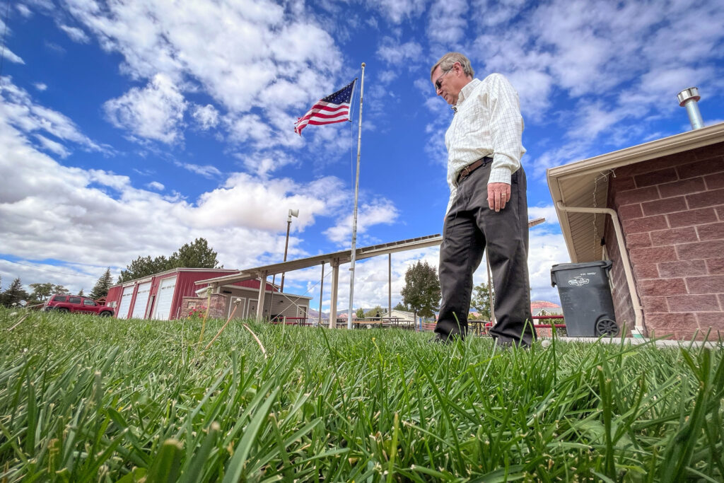 Mayor Mickey Wright walks across a patch of grass near Torrey’s city office, Sept. 29, 2025. The town plans to replace the grass with desert landscaping next year to start setting a better example with water conservation. (David Condos)