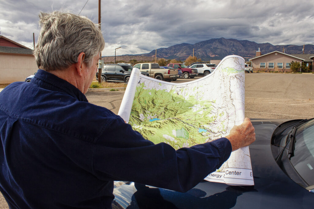 Tom Taylor of Kinetic Power displays a map of the proposed Carrizo Four Corners Pumped Storage project. In the background are the Carrizo Mountains, where the project's upper reservoir would be located. 