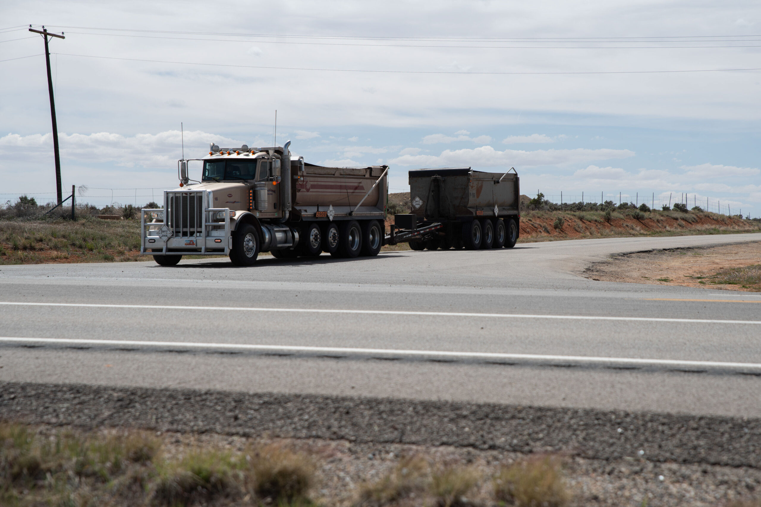 A photo of a 10-wheeler dump truck hauling a dump trailer behind it.